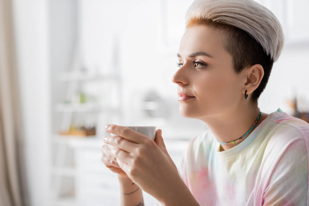 молодая и стильная женщина с чашкой кофе дома - Фото, изображение