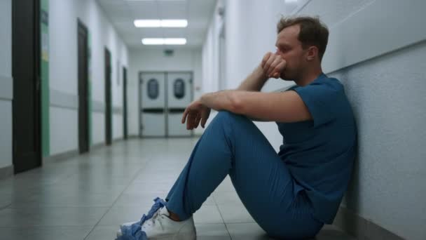 Θλιβερός γιατρός βιώνει σκληρά συναισθήματα κάθεται στο διάδρομο κλινική κοντά.  - Πλάνα, βίντεο