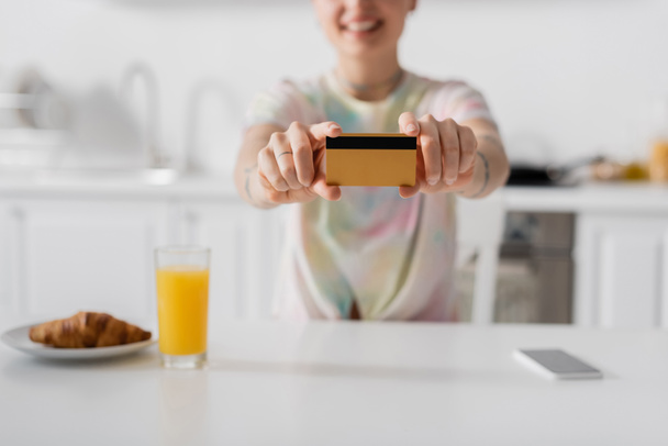 cropped view of blurred woman showing credit card near orange juice, croissant and smartphone - Photo, Image