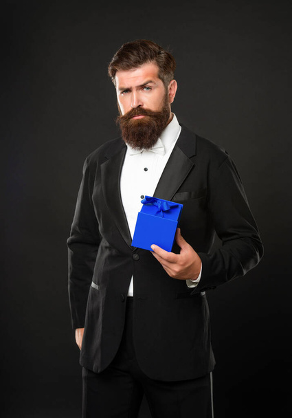 serious man in tuxedo bow tie formalwear on black background with box. valentines day - 写真・画像