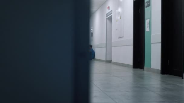 Напружений лікар сидить спираючись на настінний коридор. Втомлений медичний працівник відпочиває
. - Кадри, відео
