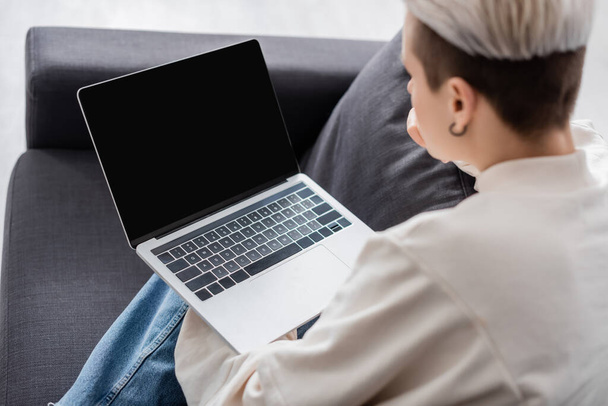 blurred woman holding laptop with blank screen and home - Foto, afbeelding
