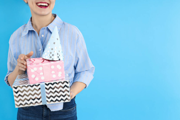 Concept van gelukkige verjaardag, jonge vrouw met geschenken op blauwe achtergrond - Foto, afbeelding