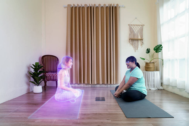 Товста жінка сидить у спілкуванні з тренером йоги у віртуальних людей на метаверсійних платформах вдома. Технологія цифрового світу паралельно з фізичною в майбутньому концепції. - Фото, зображення