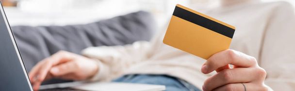 cropped view of blurred woman holding credit card near laptop, banner - Foto, Imagen