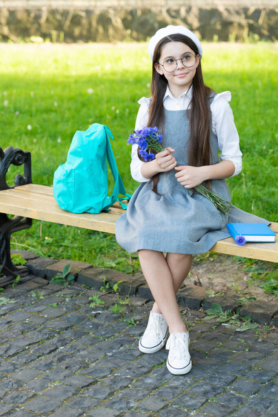 happy child in glasses relax on park bench with flowers. womens day - Fotó, kép