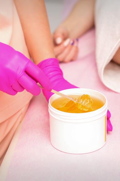 Beautician with a white jar of wax sugaring before hair removal at the spa - Photo, Image
