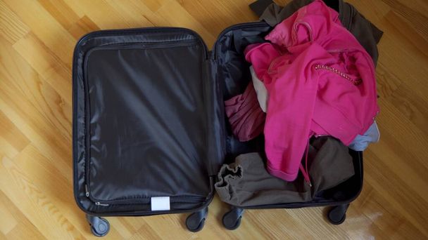 オープンスーツケースが床にあり、旅行のためのものは気軽にそれに投げ込まれます. - 写真・画像