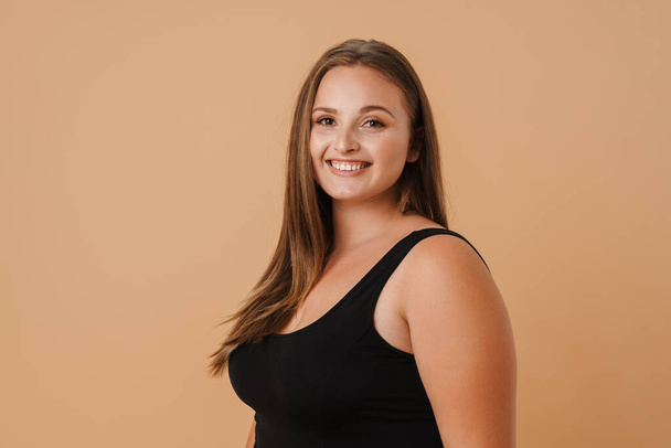 Young woman wearing swimsuit smiling and looking at camera isolated over beige background - Foto, Imagem