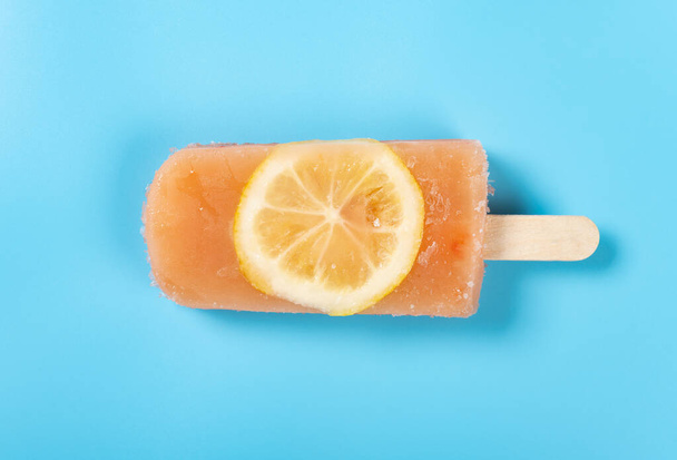 top view fresh grapefruit flavor popsicle with slice of lemon on a blue background - Photo, Image