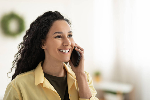 Femme souriante parlant sur un téléphone portable à la maison
 - Photo, image