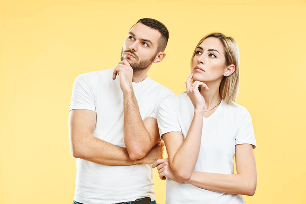 Young thoughtful man and woman looking sideways on yellow background. - Foto, Bild