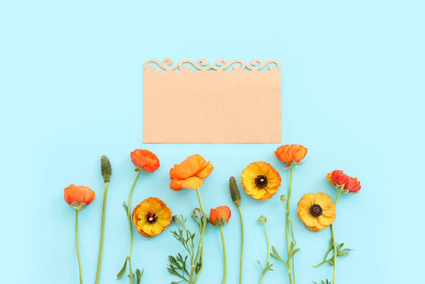 Top view image of yellow flowers composition and empty note over blue pastel background - Фото, зображення