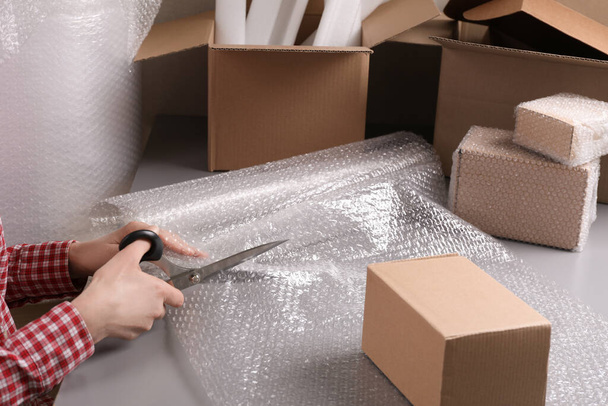 Woman cutting bubble wrap at table in warehouse, closeup - Foto, Imagem