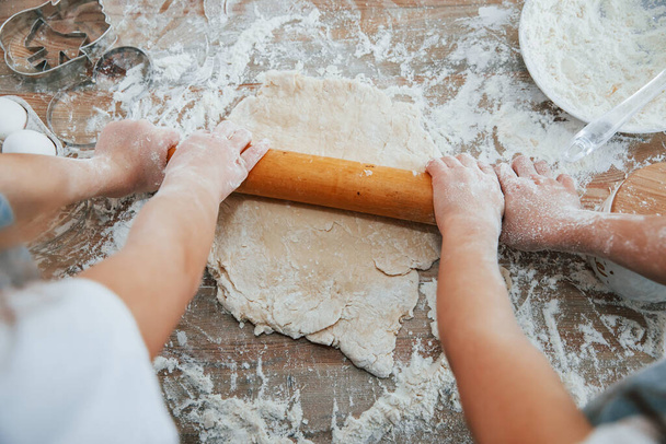 Top view of two little girl's hands that preparing knead by tool on the table. - Foto, Imagem