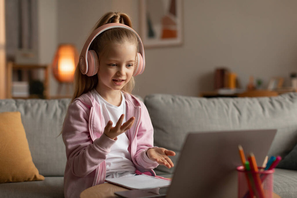 Pequena estudante fazendo chamada de vídeo via laptop aprendendo em casa - Foto, Imagem
