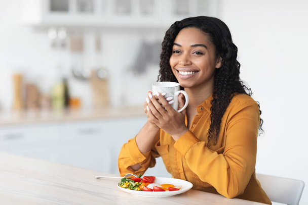 Happy black woman enjoying healthy breakfast and cup of coffee - Foto, Bild