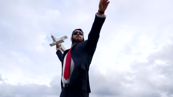 mature boss in pilot hat and glasses with plane on sky background, leadership - Záběry, video