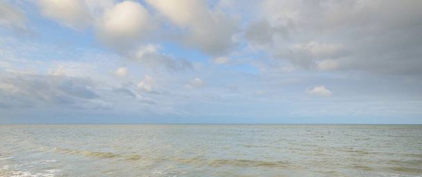 Panoramaaufnahme von der Ostseeküste bei Sonnenuntergang. Dramatische Wolkenlandschaft. Unbeständiges Wetter, Wellen und Wasserspritzer. Wintertourismus, globale Erwärmung, Klimawandel, Natur, Ökologie - Foto, Bild