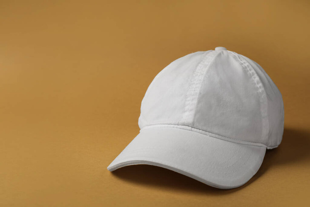 Baseball cap on brown background, space for text - Foto, Imagen