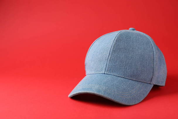 Stylish light blue denim baseball cap on red background. Space for text - Fotó, kép