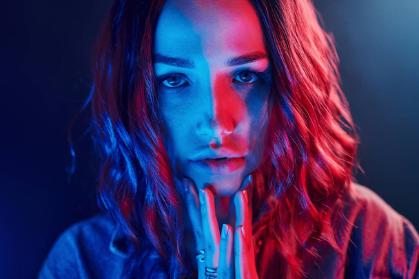 Portrait of young girl with curly hair in red and blue neon in studio. - Foto, immagini