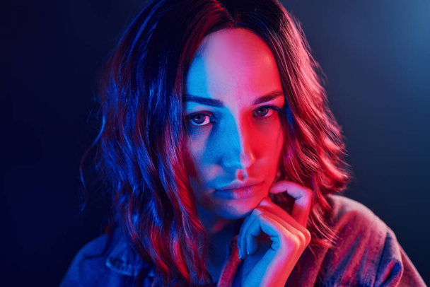 Portrait de jeune fille aux cheveux bouclés en néon rouge et bleu en studio. - Photo, image