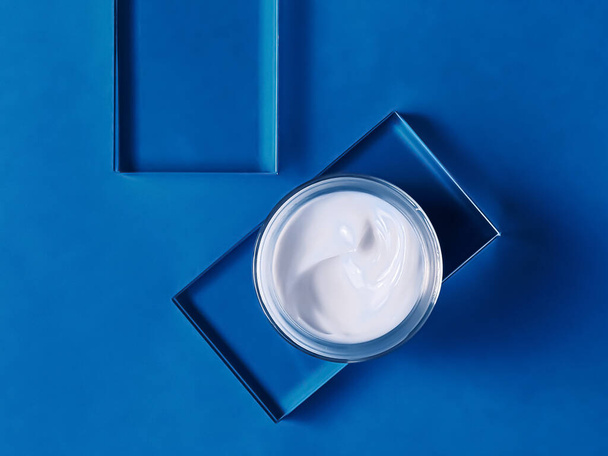 Face cream moisturiser jar on glass and blue background, beauty product and skincare, cosmetic science concept - Fotoğraf, Görsel
