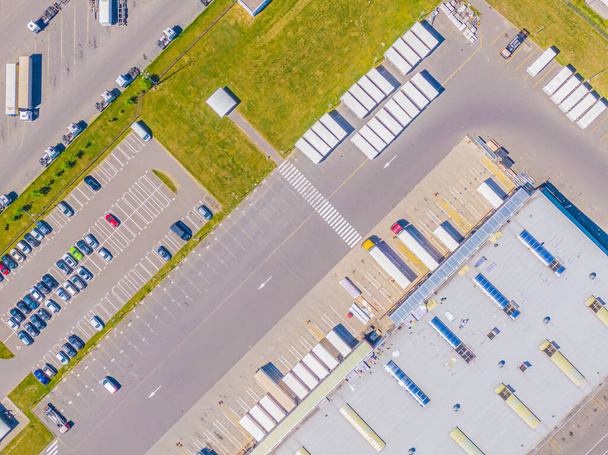 Luchtfoto van goederenmagazijn. Logistiek centrum in industriële stedelijke zone van bovenaf. Luchtfoto van vrachtwagens laden in logistiek centrum - Foto, afbeelding