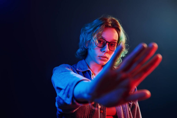 Portrait of young alternative girl in glasses with green hair in red and blue neon light in studio. - Foto, afbeelding