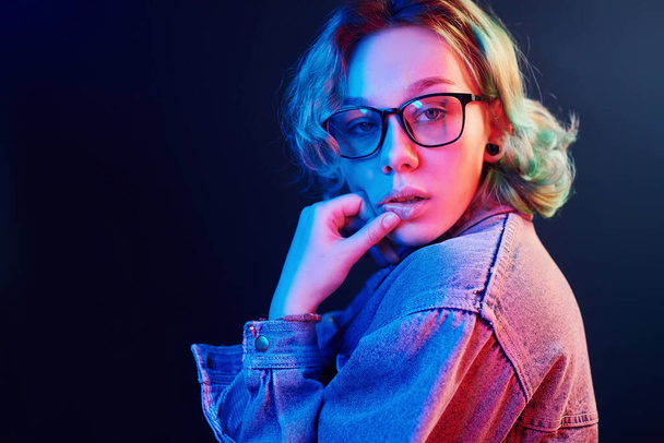 Portrait of young alternative girl in glasses with green hair in red and blue neon light in studio. - Fotografie, Obrázek