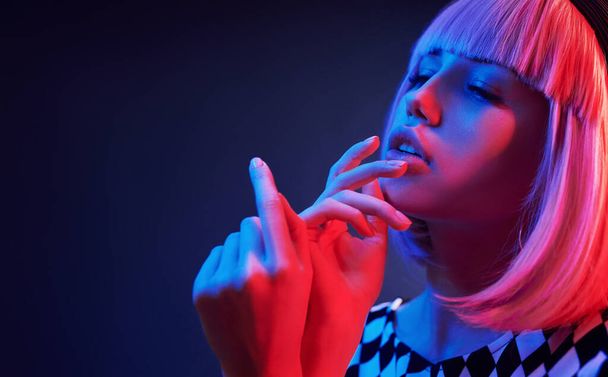Portrait of young girl with blond hair in red and blue neon in studio. - Foto, Imagen