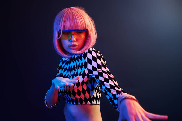 Portrait of young girl with blond hair in eyeglasses in red and blue neon in studio. - Foto, Imagen