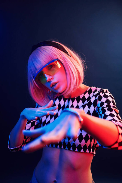 Portrait of young girl with blond hair in eyeglasses in red and blue neon in studio. - Foto, afbeelding