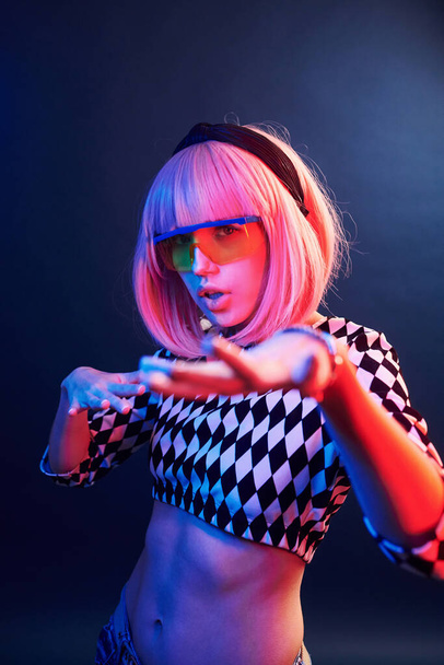 Portrait of young girl with blond hair in eyeglasses in red and blue neon in studio. - 写真・画像