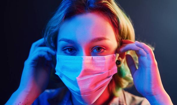 Portrait of girl that wearing protective mask on face in neon lights. - Photo, image
