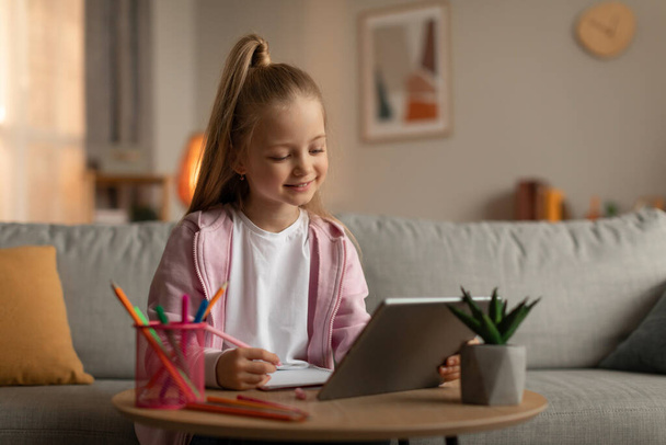 Schoolgirl Using Digital Tablet Taking Notes Learning Online At Home - Valokuva, kuva