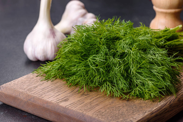 A bunch of fresh green dill on a wooden cutting board on a dark concrete background. Cooking at home - Foto, imagen