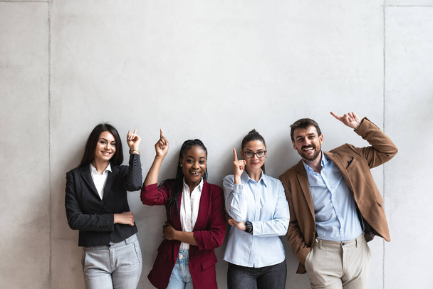 Group of young happy successful business team people pointing finger up and smiling. Freelancers or exchange students showing above and smile looking at the camera.  - Fotoğraf, Görsel