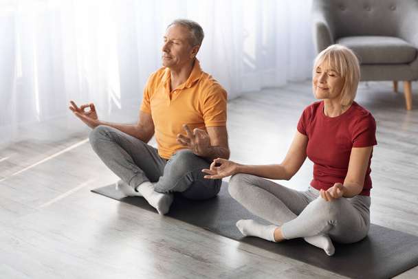 Entspanntes Senioren-Paar meditiert gemeinsam zu Hause, kopiert Raum - Foto, Bild