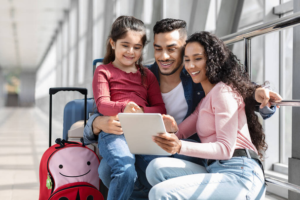 Красива молода сім'я Близького Сходу, використовуючи цифровий планшет в залі аеропорту
 - Фото, зображення