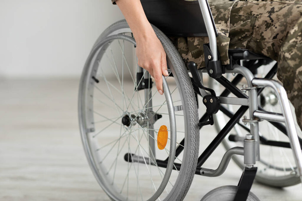 Abgeschnittene Aufnahme einer Soldatin, die in einem selbstfahrenden manuellen Rollstuhl sitzt - Foto, Bild