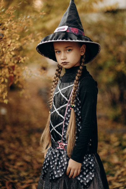 Cadılar Bayramı kutlaması. Cadılar Bayramı için hazırlanmış cadı gibi giyinmiş bir kız. Geleneksel sonbahar bayramı maskeli balosu. - Fotoğraf, Görsel