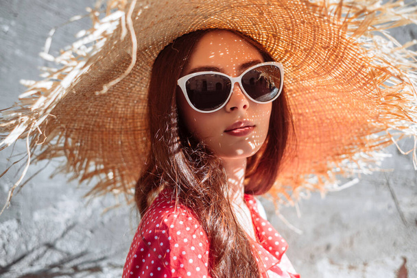 Nyári lány szalmakalapban és napszemüvegben. Divatos nő nyári portré a napsütéses napon - Fotó, kép