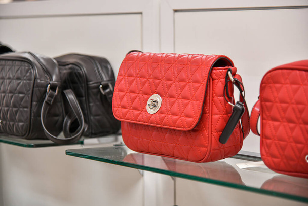 Red leather women's handbags on sale in the mall. - 写真・画像