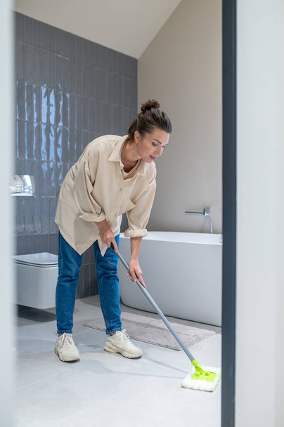 Young woman cleaning the floor at home - Foto, afbeelding