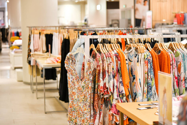 Γυναικείες μπλούζες διαφορετικού χρώματος κρέμονται σε μια κρεμάστρα για πώληση σε εμπορικό κέντρο. - Φωτογραφία, εικόνα