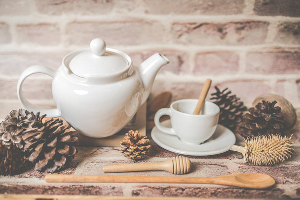 Conceito de chá, bule branco com xícara de chá branco com folhas secas no fundo de madeira, vista de lado. produto orgânico da natureza para saudável com tradicional. - Foto, Imagem