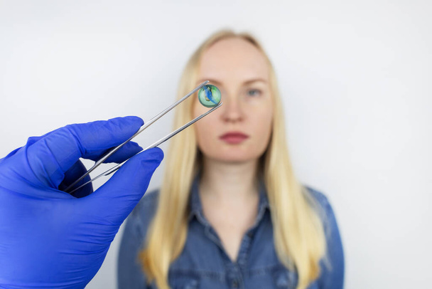 Göz kristal lens değişiminin kavramsal görüntüsü. Ototimik cerrahi. Görüş alanına geri dön. Kataraktların çıkarılması. Gözüne cerrahi müdahale. Doktor implantı hastanın yanında tutuyor. - Fotoğraf, Görsel
