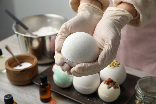 Woman in gloves with self made bath bomb at table, closeup - Foto, Imagem